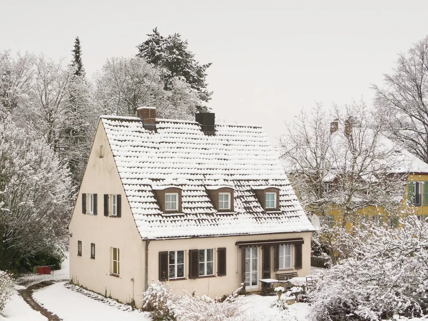 Einfamilienhaus im Schnee zwischen verschneiten Bäumen